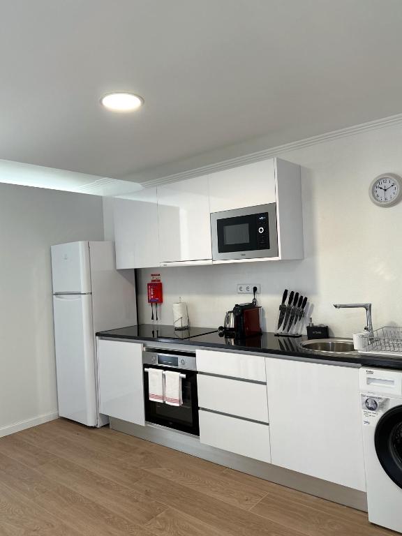 uma cozinha com armários brancos e um frigorífico branco em Madeiran Sweet Home no Funchal