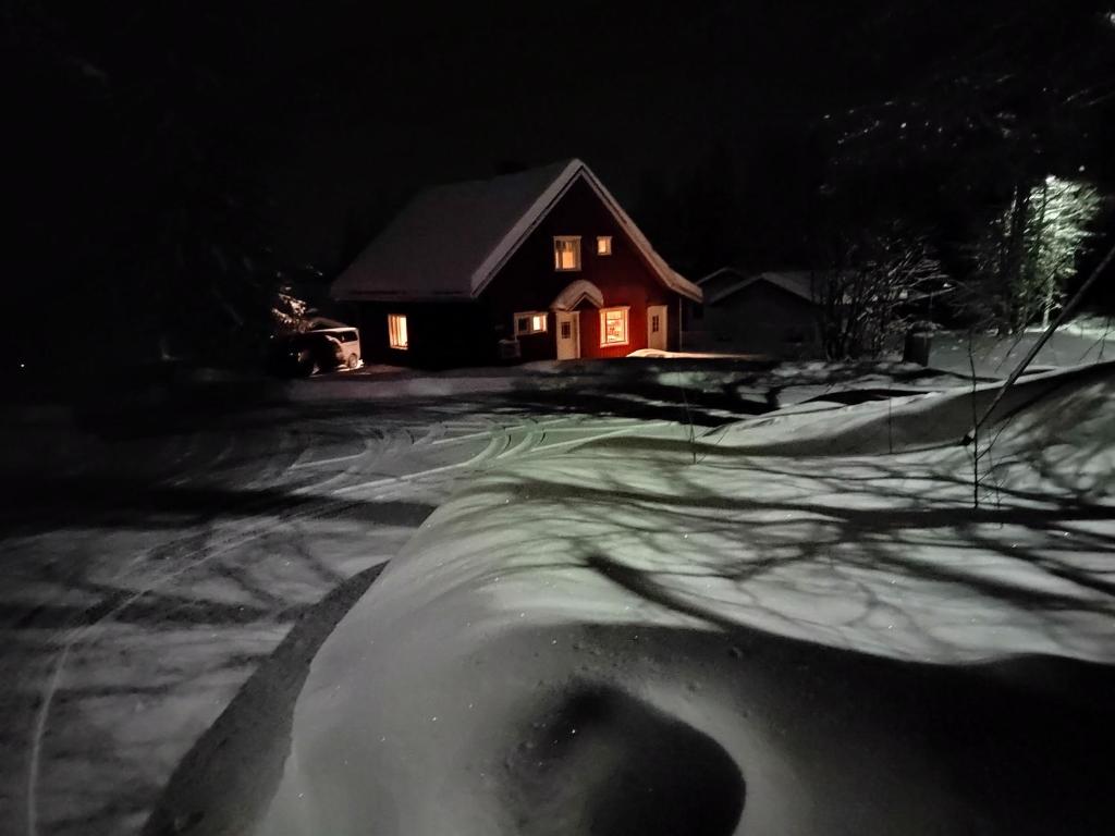 una casa con mucha nieve delante de ella en Villa Haaveranta - Cosy cabin by the lake, en Rovaniemi