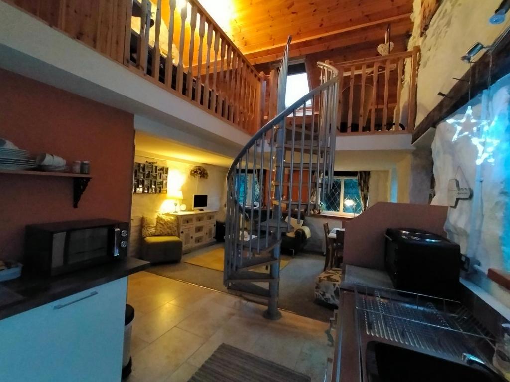 a living room with a spiral staircase in a house at Yr Hen Efail - Quirky Old Smithy cottage near forest walks, cycling & lakes in Garthbeibio