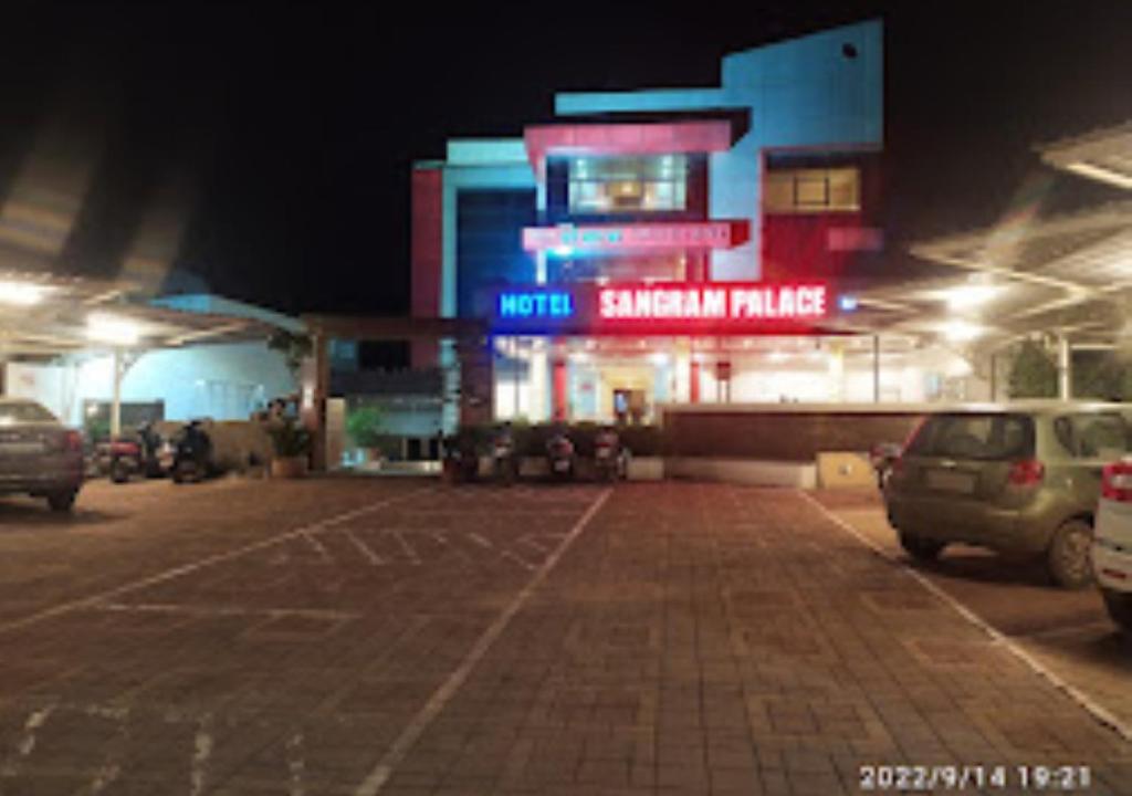 una gasolinera por la noche con coches aparcados en un aparcamiento en Hotel Sangram Palace Shirur, en Sirūr