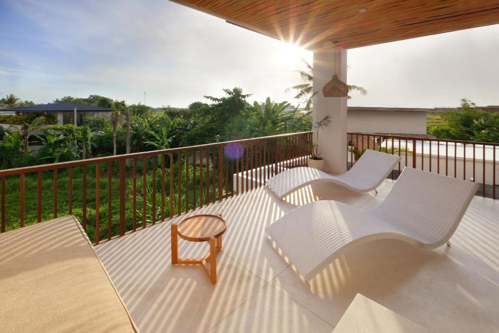 balcone con sedie bianche, tavolo e ringhiera di Sore Pererenan Residence Unit 1 a Canggu