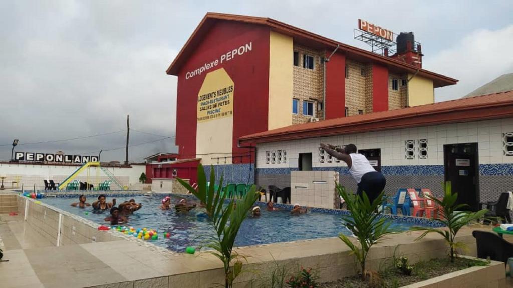 Eine Person, die mit Leuten in einen Pool springt. in der Unterkunft Complexe Meublé PEPON in Douala