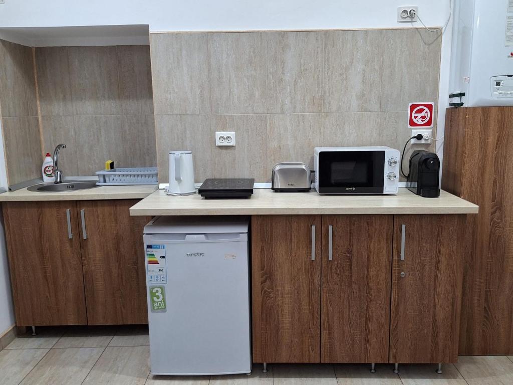 a kitchen with a counter with a microwave and a refrigerator at Cluj Memorandumului Apt ultracentral cu parcare privata in Cluj-Napoca