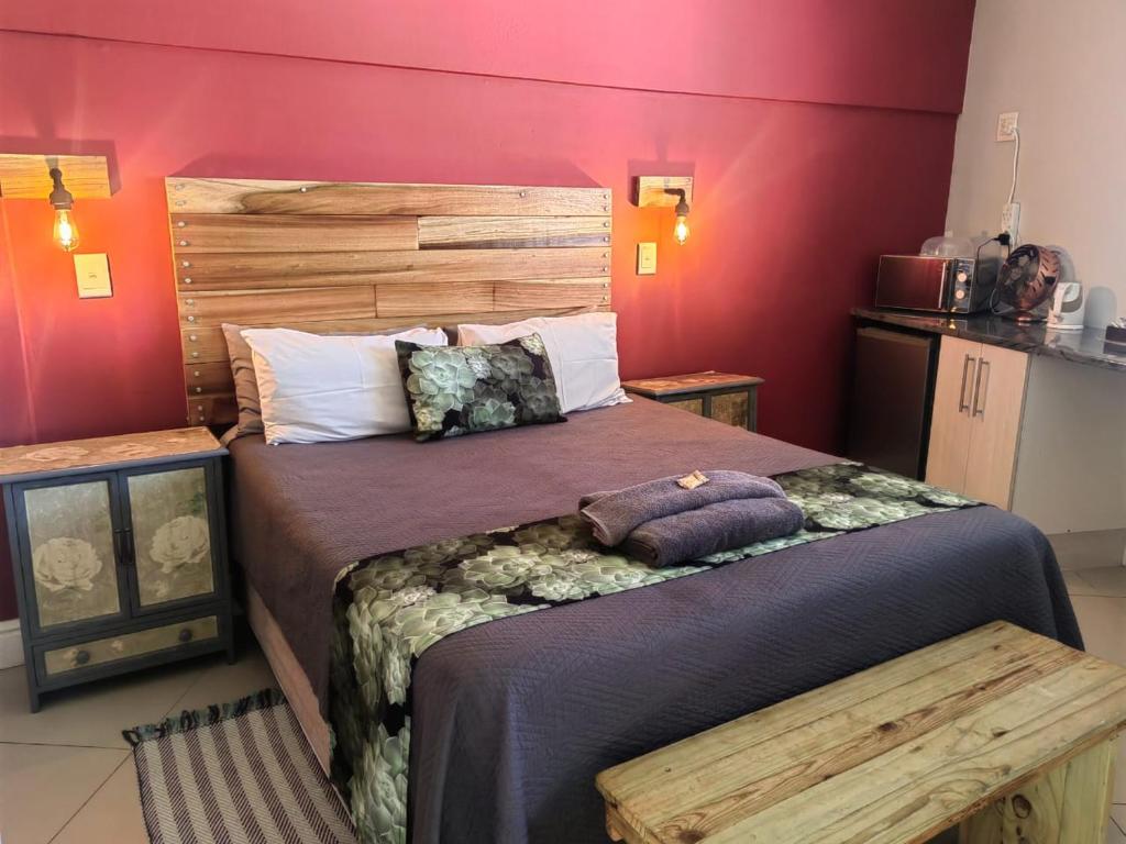 Schlafzimmer mit einem großen Bett mit einem Kopfteil aus Holz in der Unterkunft @47 Galpin in Port Elizabeth