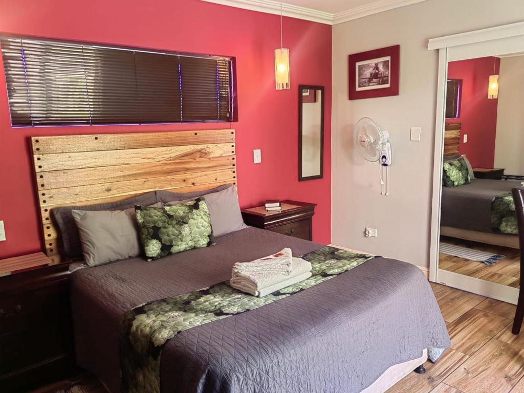 1 dormitorio con cama y pared roja en @47 Galpin en Puerto Elizabeth
