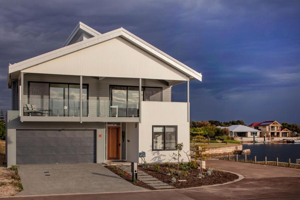 a house with a garage in front of the water at Port Lane Townhouse in Geographe
