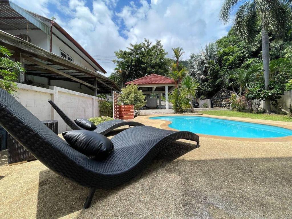 a black hammock sitting next to a swimming pool at Kata Sea Blue Villa in Kata Beach