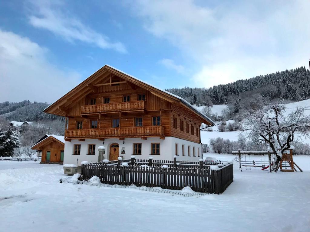 a house with a wooden roof in the snow at Apartment Hinkerhof in Schladming