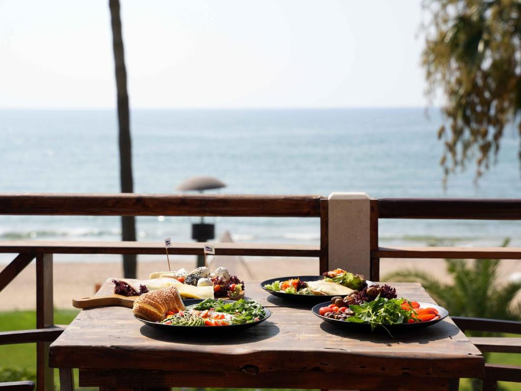 a wooden table with three plates of food on it at Laguava Resort in Ar Rumaylah