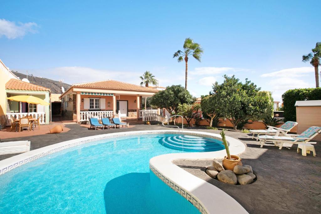 a swimming pool with chairs and a house at Eveas in Candelaria