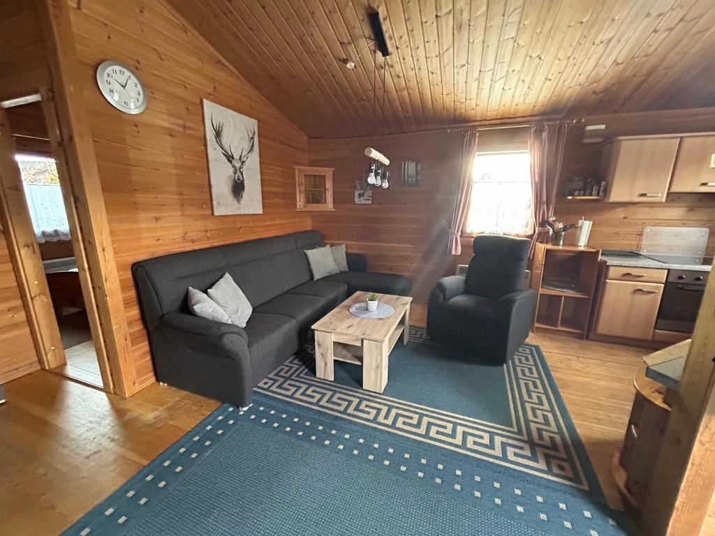 uma sala de estar com um sofá e uma mesa em Ferienhaus Nr 10, Typ A, Feriendorf Jägerpark, Bayerischer Wald em Viechtach