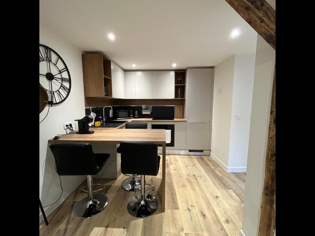 - une cuisine avec un comptoir et quelques chaises dans l'établissement Tonnelet Rouge - Appt au cœur de la ville, à Strasbourg