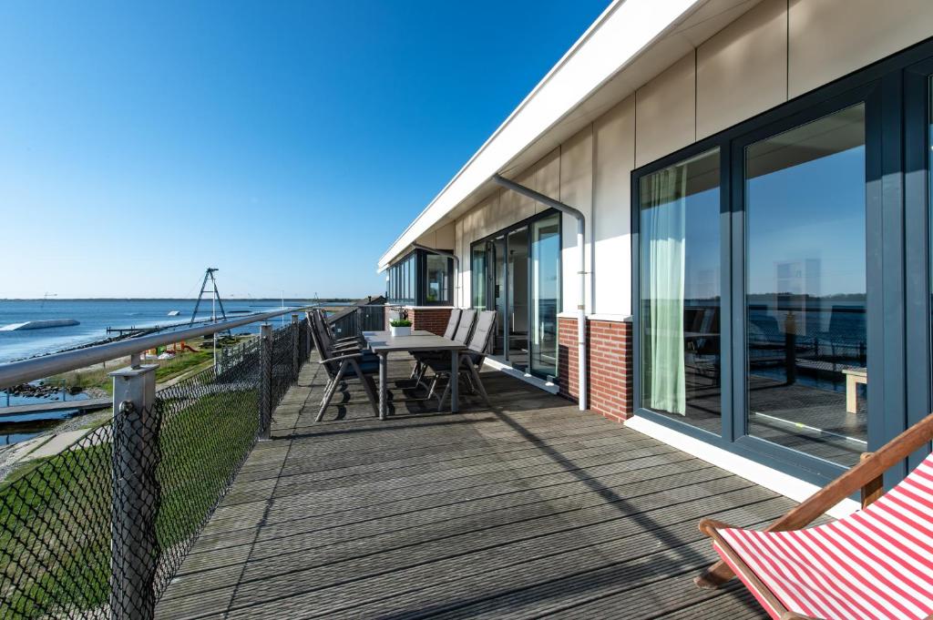 a deck with a table and chairs on the beach at Penthouse XL Veerse Meer in Kamperland