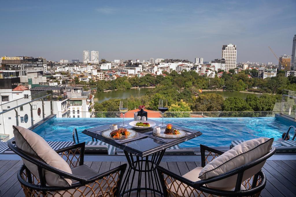 a table and chairs on a balcony with a view of a city at The Oriental Jade Hotel in Hanoi