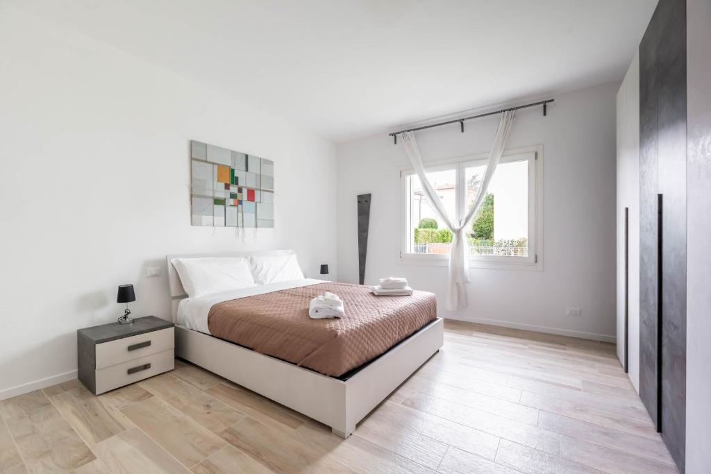a white bedroom with a bed and a window at Italstay - Guerrazzi New Flat - Parcheggio privato in Padova