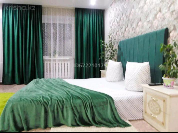 a bedroom with a bed with a green blanket on it at Центр 1ком студия ЖД вокзал М.Маметова in Oral