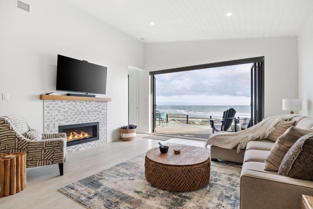 a living room with a fireplace and a view of the ocean at Beachfront Luxury Suite #15 at THE BEACH HOUSE in Campbell River