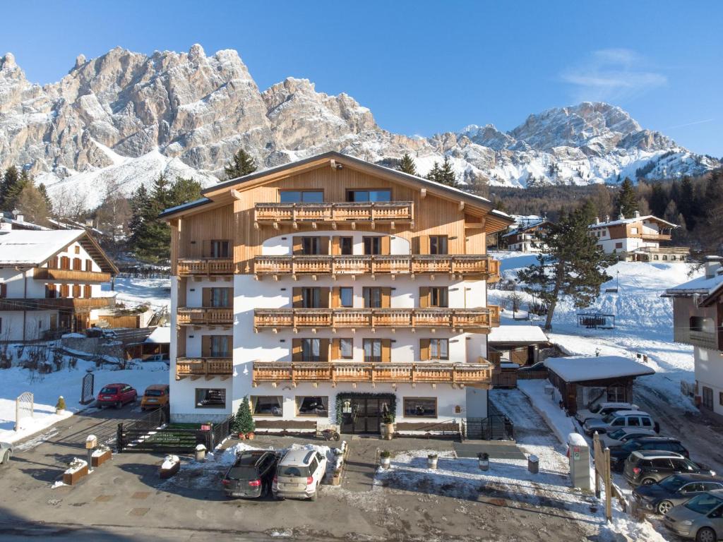 a hotel with cars parked in a parking lot with mountains at Camina Suite and Spa in Cortina dʼAmpezzo
