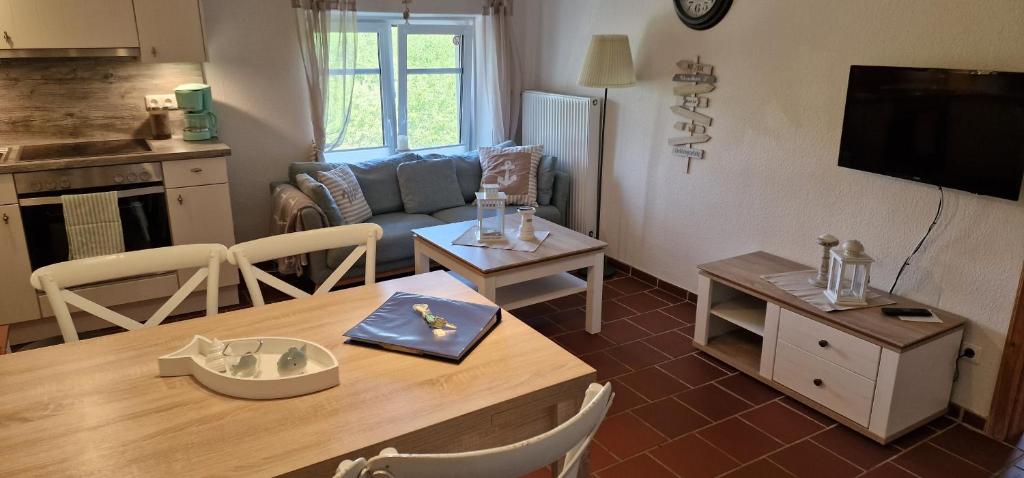 uma cozinha e sala de estar com uma mesa e uma sala de estar em Ferienwohnung 'Gelting' - Refugium Pottloch Ostsee em Kronsgaard