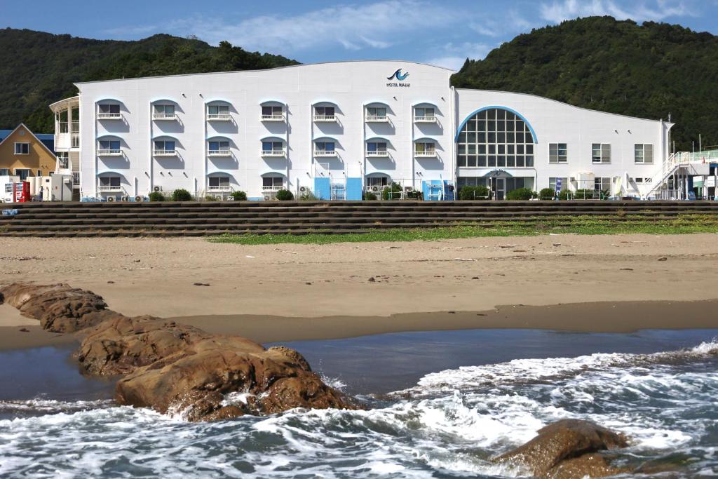 un gran edificio blanco en la playa con el agua en Hotel NALU　ホテルナル, en Kannoura