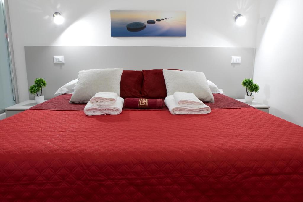 Un dormitorio con una cama roja con toallas. en Luxury Suite - Teatro Romano - Duomo - Centro Storico Wi-Fi en Terracina