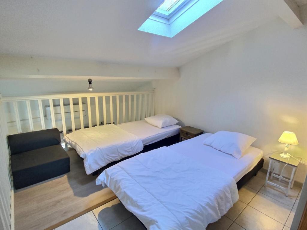 Duas camas num pequeno quarto com uma clarabóia. em Petit pavillon pour 6 personnes dans une résidence avec piscine em Valras-Plage