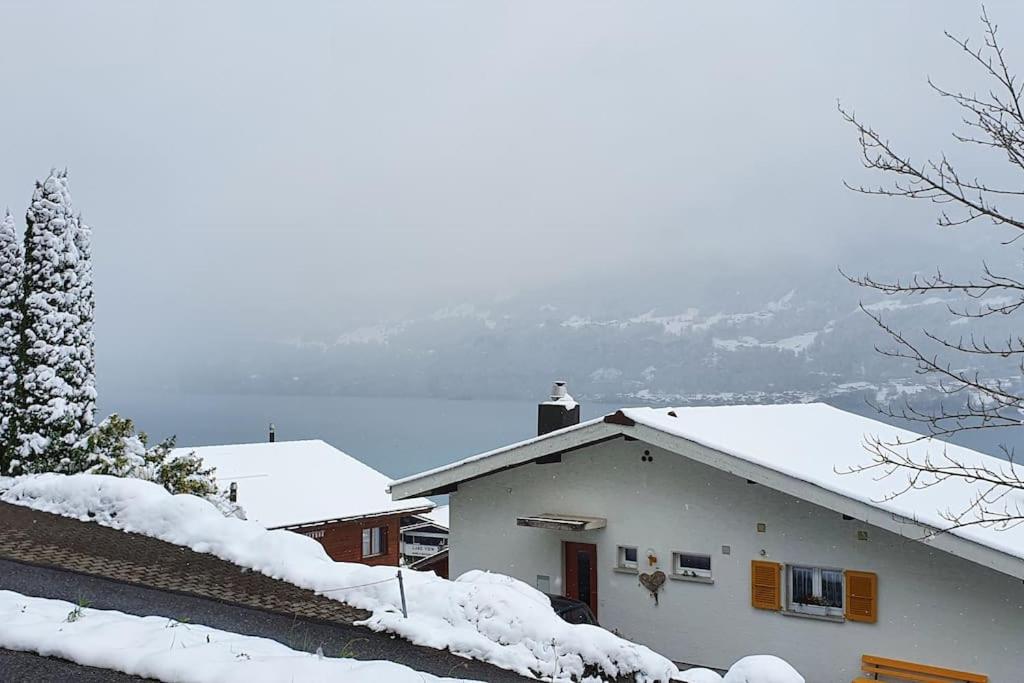 uma casa branca com neve no telhado em Lakeview Basement Apartment near Interlaken em Niederried