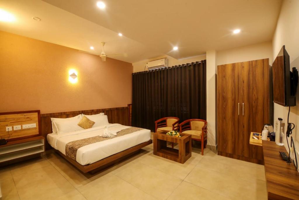 a bedroom with a bed and a table and a chair at ARIAT AVENUE in Wayanad