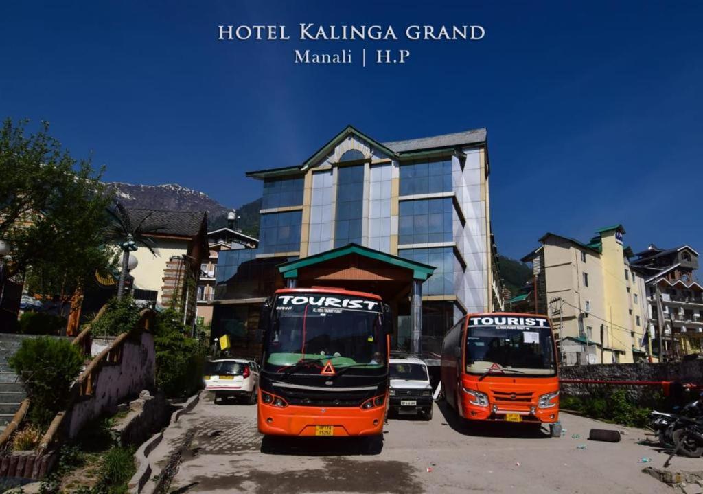 dois autocarros estão estacionados em frente a um edifício em Hotel Kalinga Grand - Top Rated Most Awarded Property In Manali em Manali