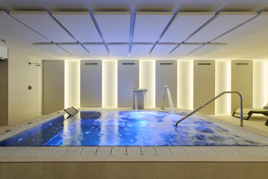 a large swimming pool with blue water in a building at Catalonia La Maquinista in Barcelona