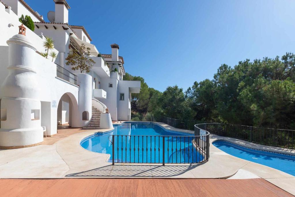 a villa with a swimming pool in front of a building at Golf Duplex con piscina en La Quinta Golf Marbella in Málaga