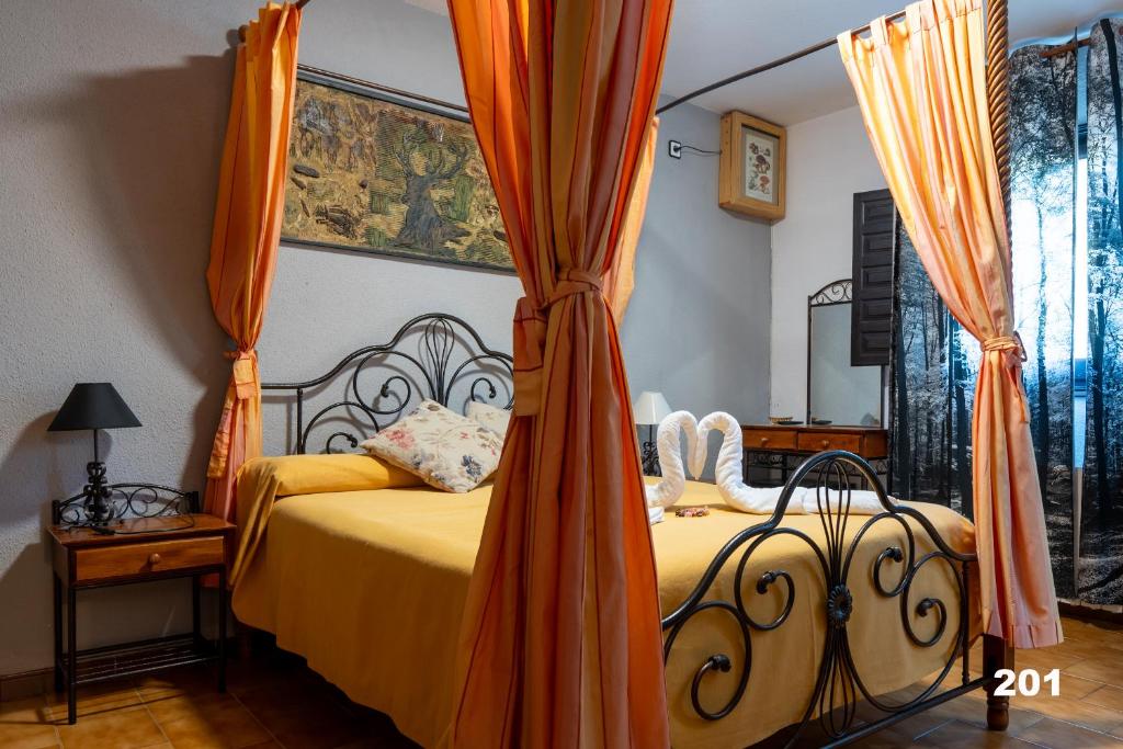 een slaapkamer met een bed met een oranje baldakijn bij Hotel Uña Serranía Encantada in Uña