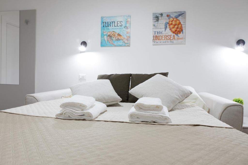 Una cama blanca con toallas encima. en Incantevole Loft - Centro Storico- Wi-Fi- Ad un passo da tutto, en Terracina