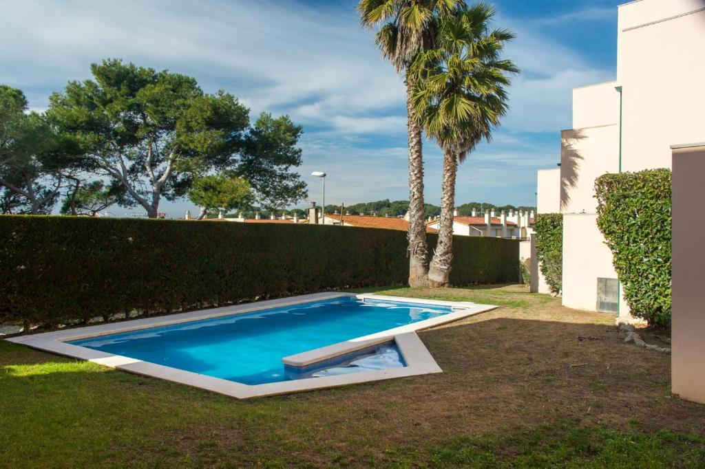 a swimming pool in a yard with palm trees at Costabravaforrent Pedró in L'Escala