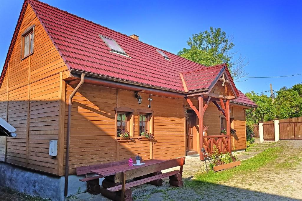 een houten huis met een bank ervoor bij Chata pod Mogielicą in Zalesie
