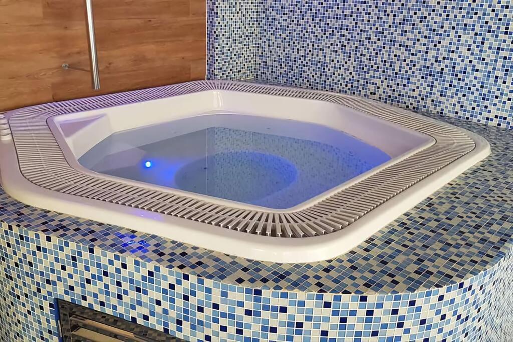 a bath tub in a bathroom with a tiled floor at Upmarket Beach Flat, Free WiFi & DisneyPlus in Durban