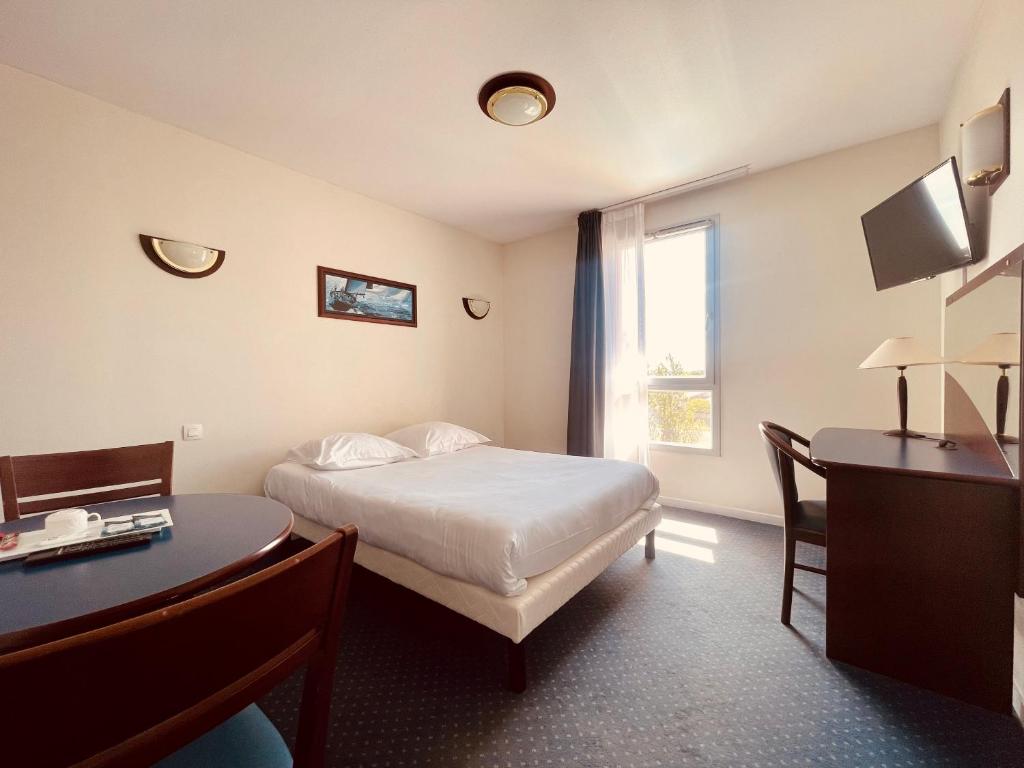 Cette chambre comprend un lit, un bureau et une fenêtre. dans l'établissement Zenitude Hôtel-Résidences Carcassonne, à Carcassonne