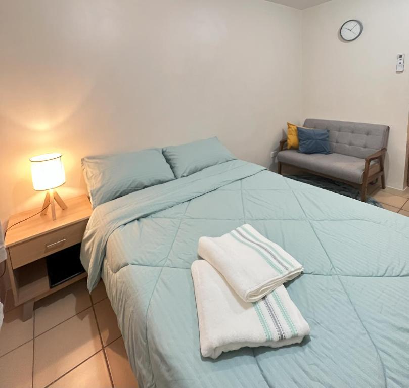 ein Schlafzimmer mit einem blauen Bett und Handtüchern darauf in der Unterkunft New 8 Spatial Davao Smart Studio Unit Netflix Wi-Fi Amazon Voice Controlled Lights in Davao City
