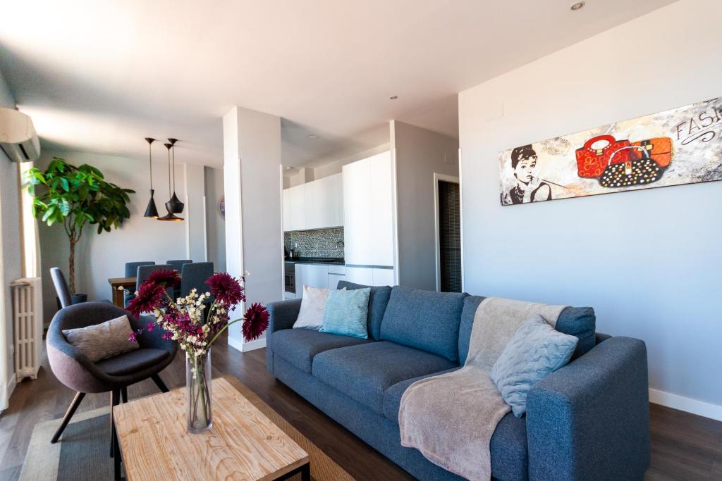 sala de estar con sofá azul y mesa en Noa Apartment, en Madrid
