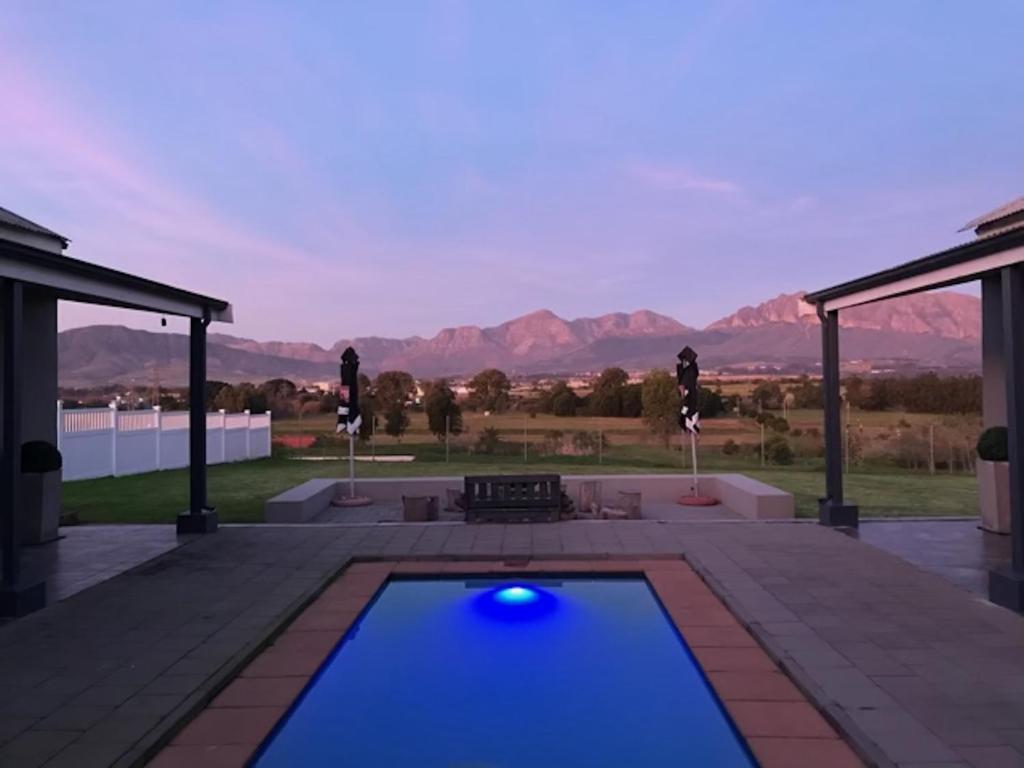a swimming pool on a patio with mountains in the background at Mooi Uitsig Lodge in Paarl