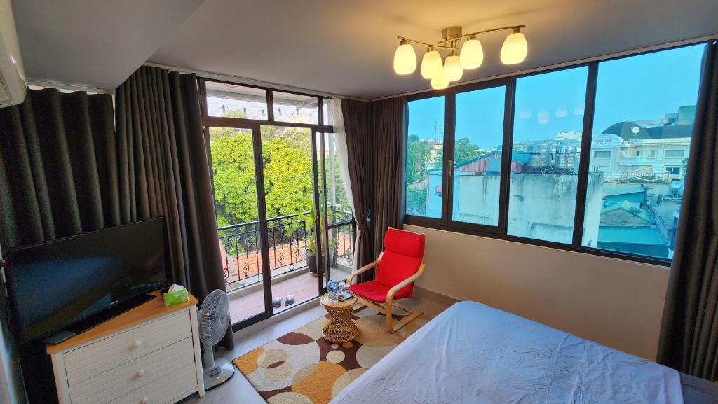una camera da letto con una sedia rossa e una grande finestra di T Home Balcony Homestay a Hanoi