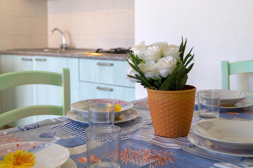 una mesa con un jarrón de rosas blancas. en Libeccio Sea view house, en Badesi