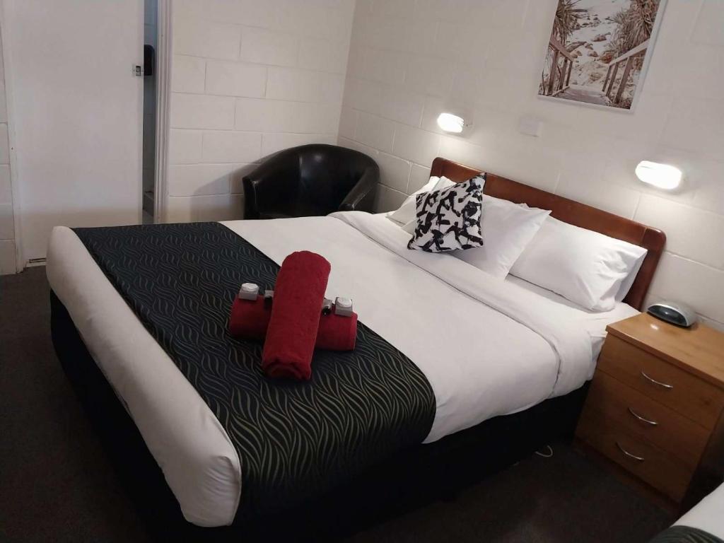 1 dormitorio con 1 cama con 2 almohadas rojas en Golden Peak Motel PeakHill, en Peak Hill