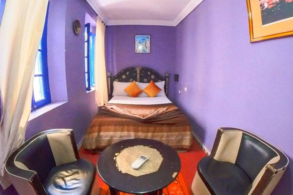 Habitación púrpura con 1 cama y 2 sillas en RIAD DAR LFONOUN en Marrakech