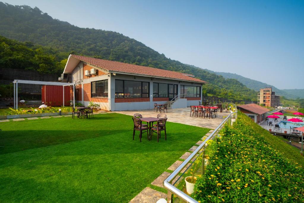 a building with chairs and tables on a green lawn at Gaurav Lords Resort in Srīvardhan