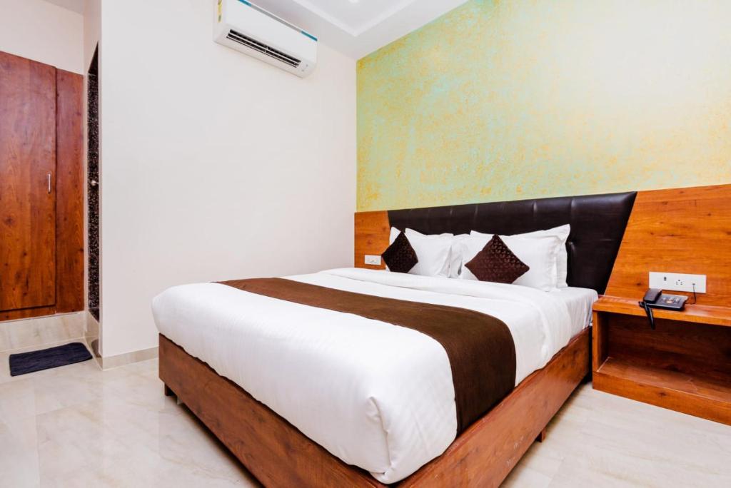 a bedroom with a large bed with a wooden headboard at Hotel Raheja Residency in Mumbai