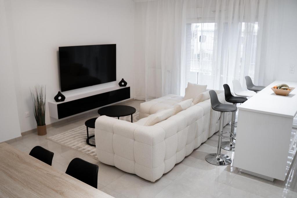 a white living room with a white couch and a tv at Appartement Paris La Défense U Arena in Nanterre