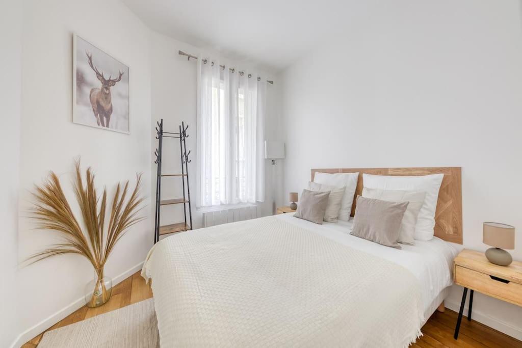 ein weißes Schlafzimmer mit einem großen Bett und einer Pflanze in der Unterkunft Le Paisible Parisien à 3 minutes du métro in Vincennes