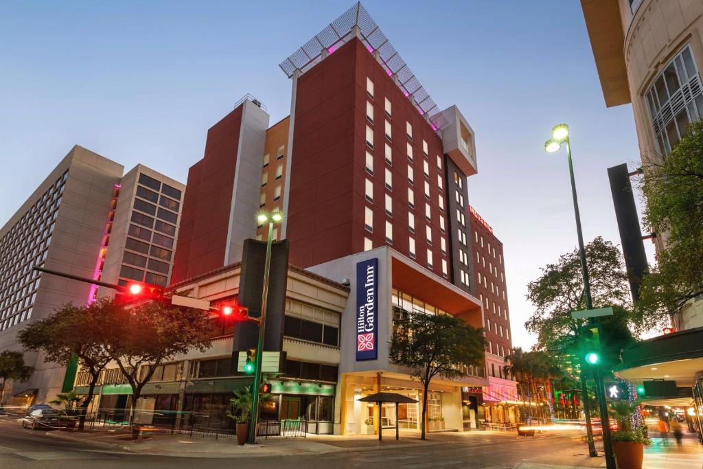 聖安東尼奧的住宿－Hilton Garden Inn San Antonio Downtown Riverwalk，夜幕降临的城市街道上一座高大的红色建筑
