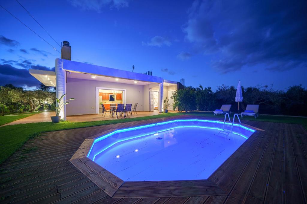 una piscina di fronte a una casa di notte di Villa Lima Pool & Jacuzzi Chania a Vamos